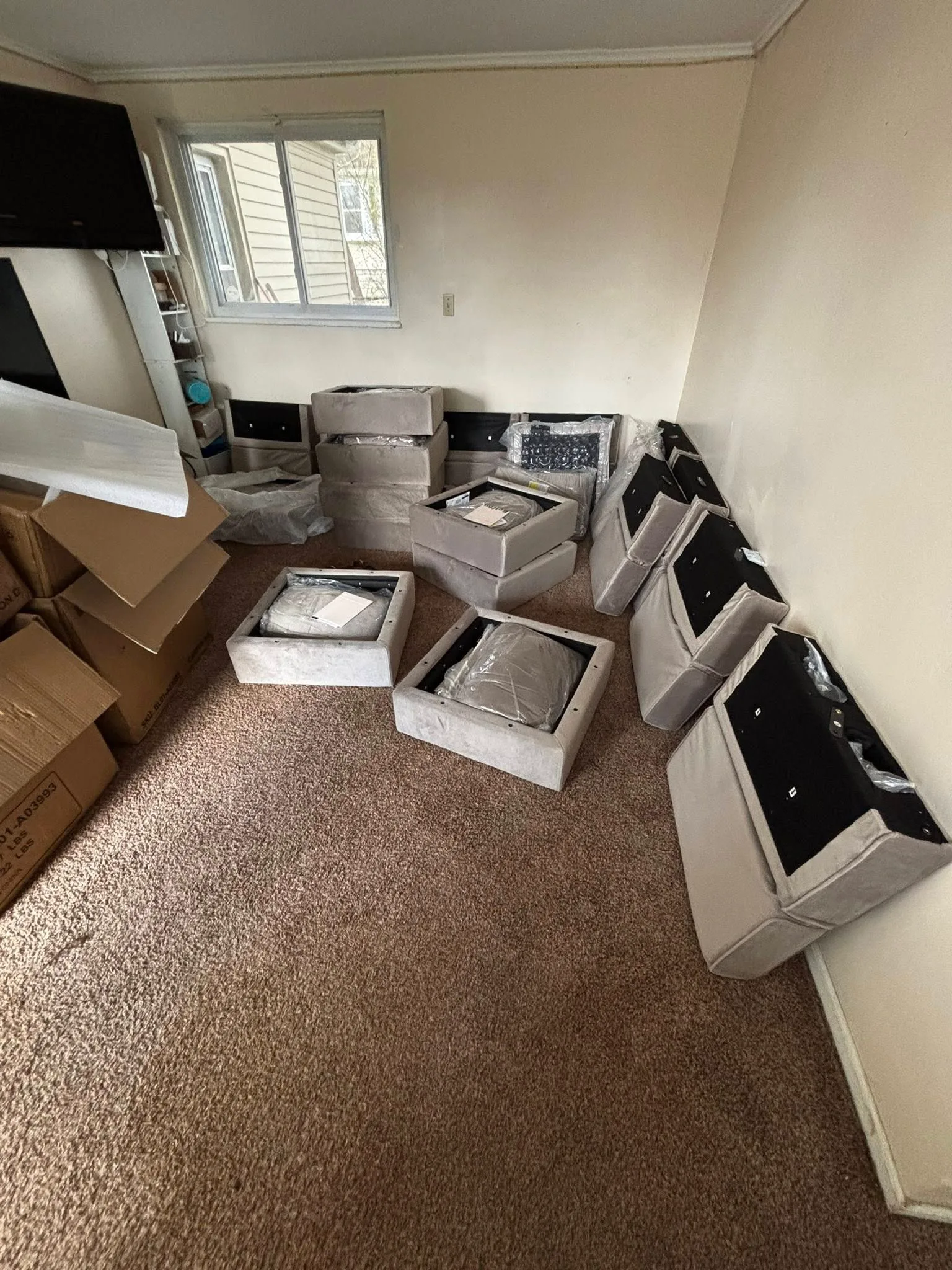 Sectional sofa parts still in cardboard boxes scattered across an empty room.